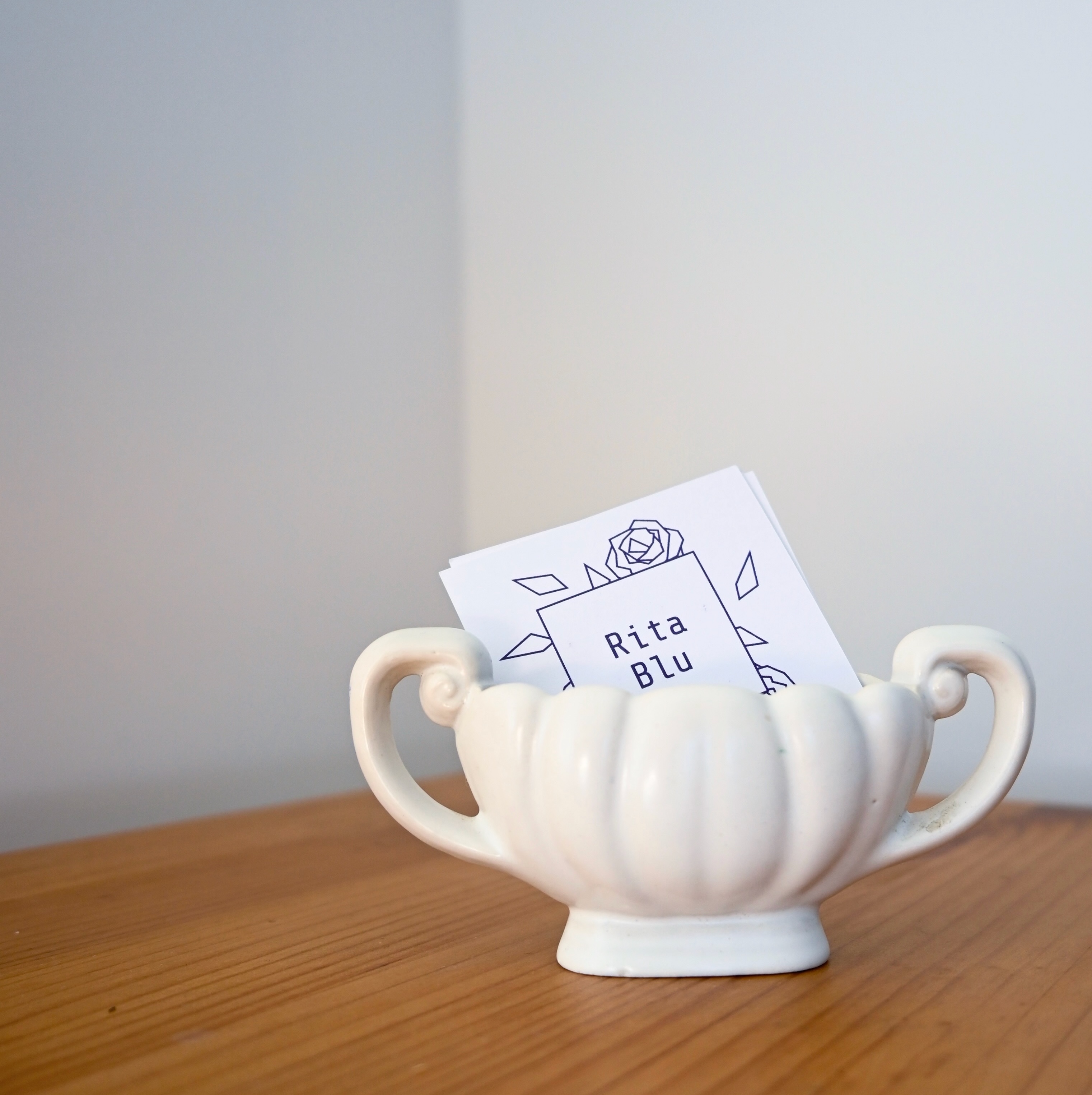A stack of square cards with the Rita Blu logo printed on them in a small bowl